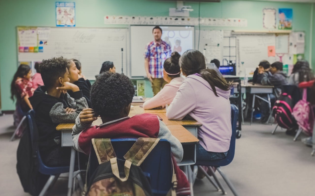 male teacher in a classroom full of diverse students